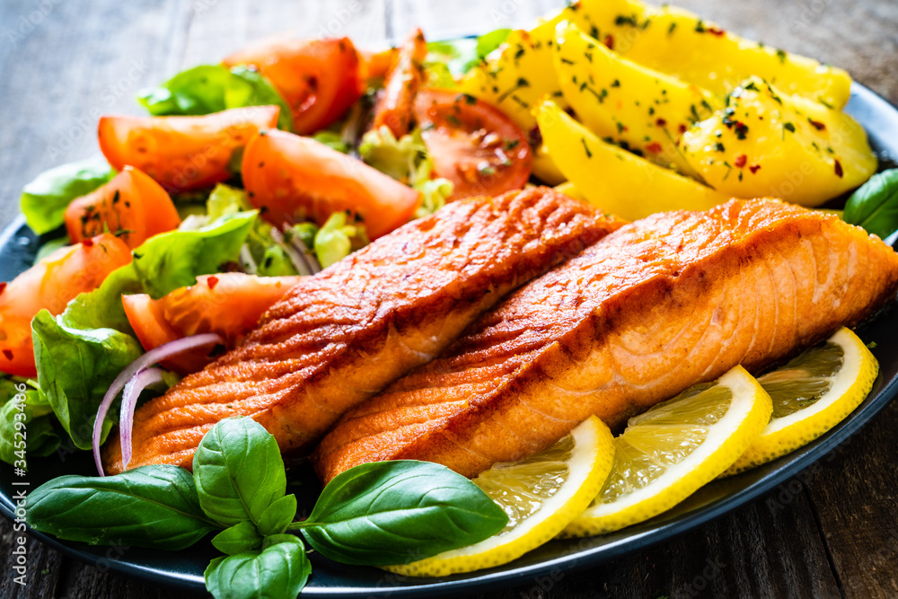 Fried salmon steak with potatoes and vegetables on wooden table
Fried salmon steak with potatoes and vegetables on wooden table