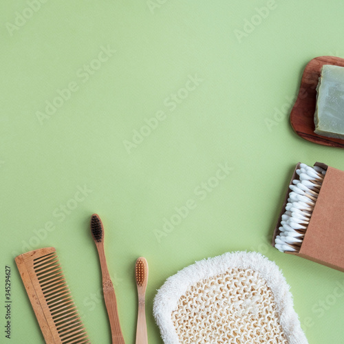 Eco friendly set products on green background. Bamboo toothbrushes  cotton buds  comb  natural soap and washcloth. Top view  flat lay  copy space