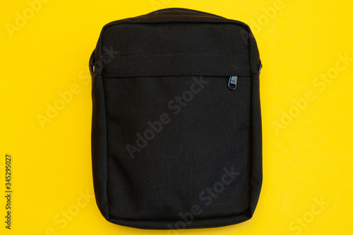 close up male black bag on yellow background, trendy minimal place for text photo