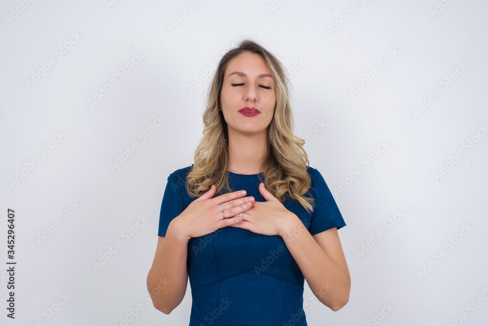 Faithful woman closes eyes and keeps hands on chest near heart, shows her kindness or favour, expresses sincere emotions, being kind hearted and honest. Body language and real feelings concept Faithful woman closes eyes and keeps hands on chest near heart, shows her kindness or favour, expresses sincere emotions, being kind hearted and honest. Body language and real feelings concept