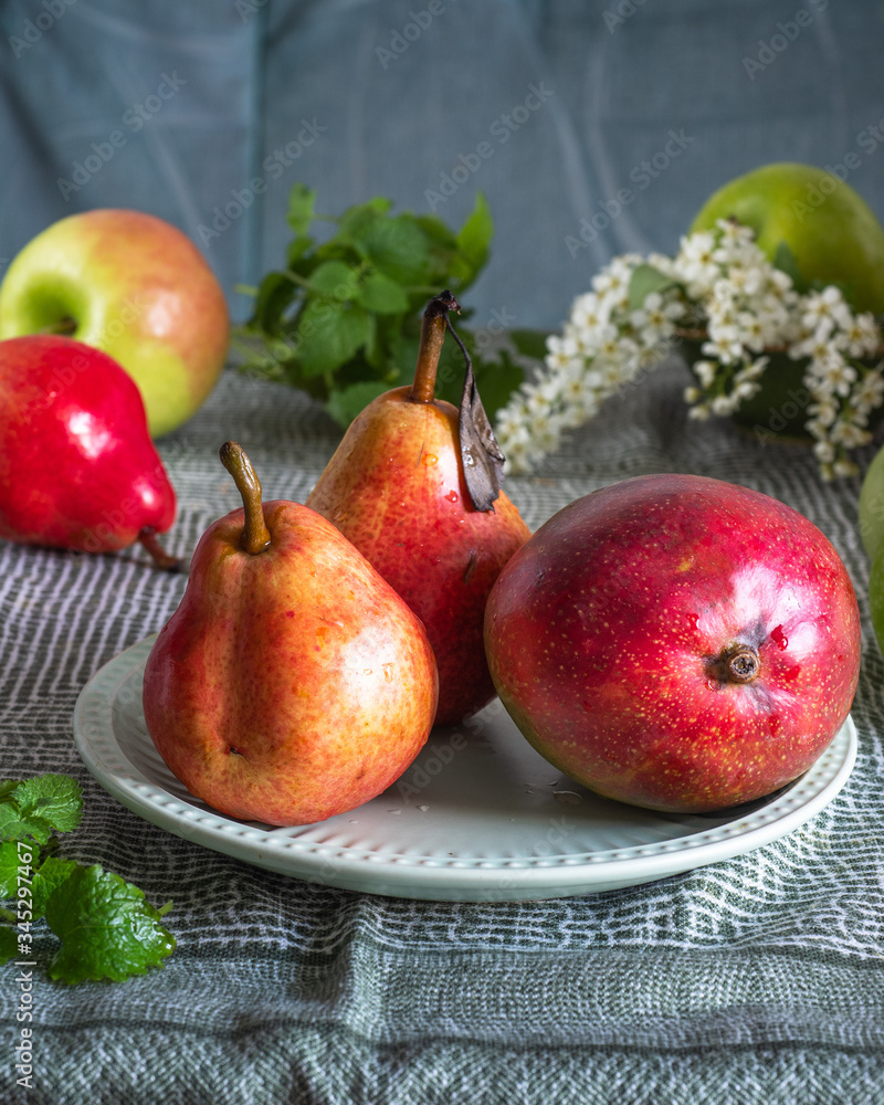 Fruit set on a green tablecloth, apples, pears and mango with sprigs of mint Fruit set on a green tablecloth, apples, pears and mango with sprigs of mint