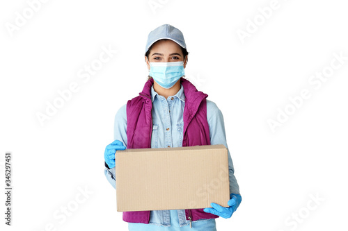 Young hispanic latin woman courier worker wears medical face mask, gloves looking at camera delivering parcel holding delivery box in hands concept stand isolated on white studio background. Portrait