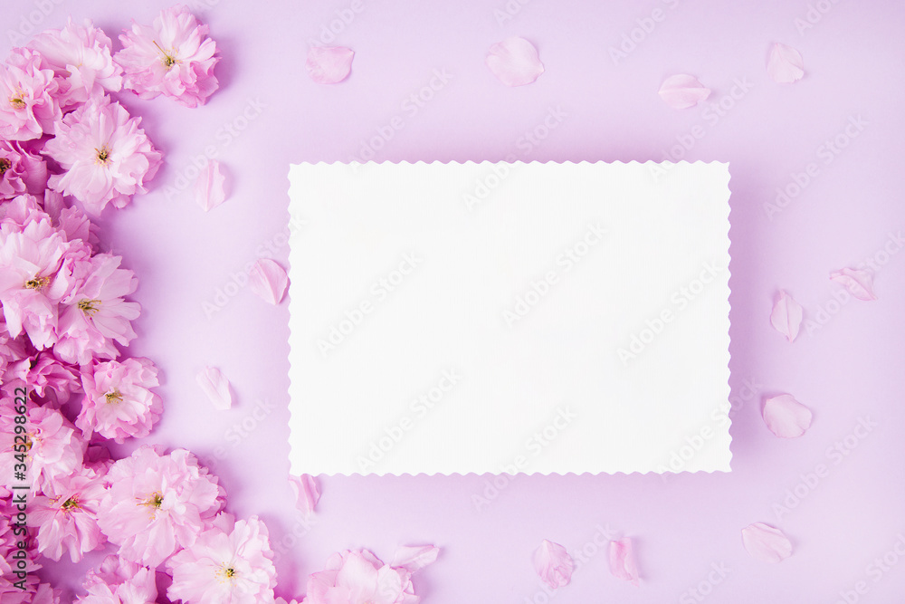 Blank paper and cute pink flowers on pink background