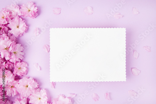 Blank paper and cute pink flowers on pink background © Julia