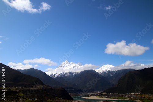 The Nanjiabawa Peak  which is hidden in the mountains and wild peach blossoms  is even more precipitous against the blue sky  white clouds  and green water 