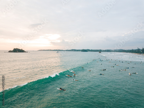 Photography WELIGAMA, SRI LANKA Unidentified surfing on a large wave on Weligama beach on the coast of Indian ocean