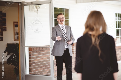 Фотография Man in suit handing out a church pamphlet to a woman
