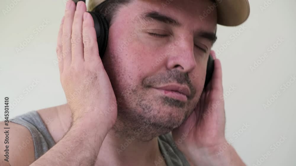 Portrait of unshaven 40 years old caucasian man enjoy listen with closed eyes to romantic slow music by wireless black headphones at home. Portrait of unshaven 40 years old caucasian man enjoy listen with closed eyes to romantic slow music by wireless black headphones at home.