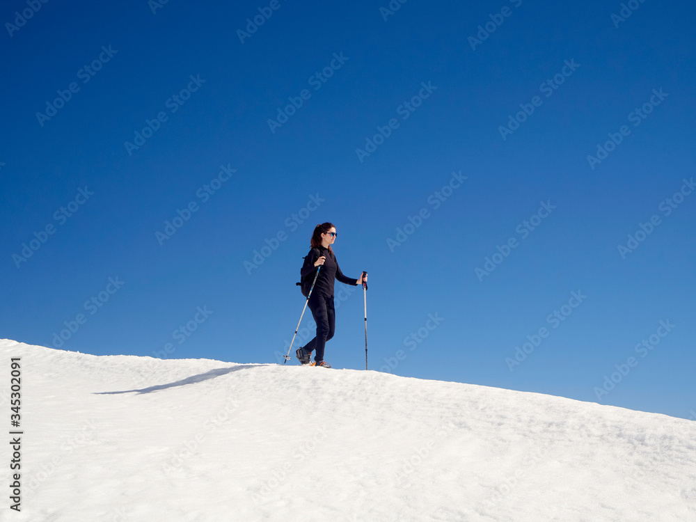 Woman snowshoeing in San Isidro, León, Spain on a sunny day. Blue sky. White snow. Women's empowerment. Female power