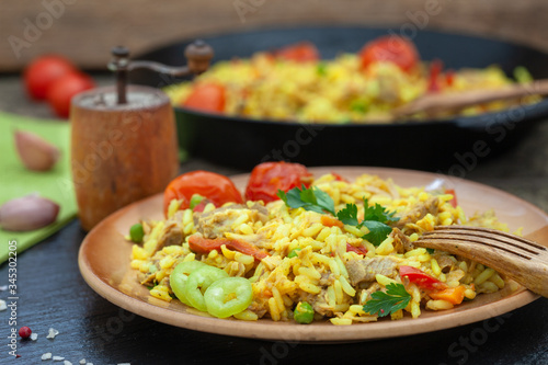 Homemade pilaf with meat, rice and vegetables on a wooden table. Oriental cuisine.