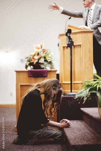Quadro su tela Woman at the front of a church kneeling down and praying