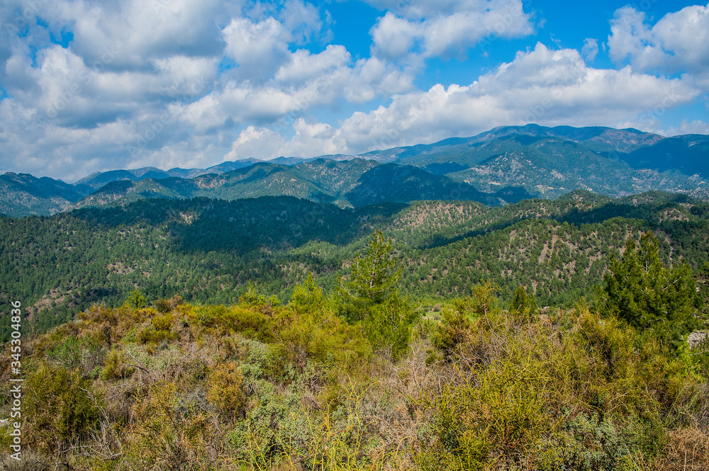 Fototapeta premium Light clouds cast fancy shadows on the peaks and slopes of the Troodos Mountains. Shadows creep from mountain to mountain, changing their shape. 