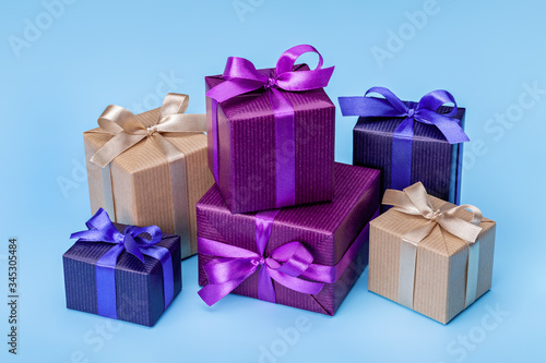 A set of gifts and surprises in bright boxes decorated with ribbons with bows. On blue background, copy space.