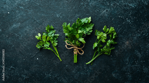 Fresh green parsley on black stone background. Top view. Free space for your text.