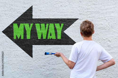 Ein blonder Junge vor einer Wand mit schwarzem Pfeil und dem grünen Text MY WAY photo