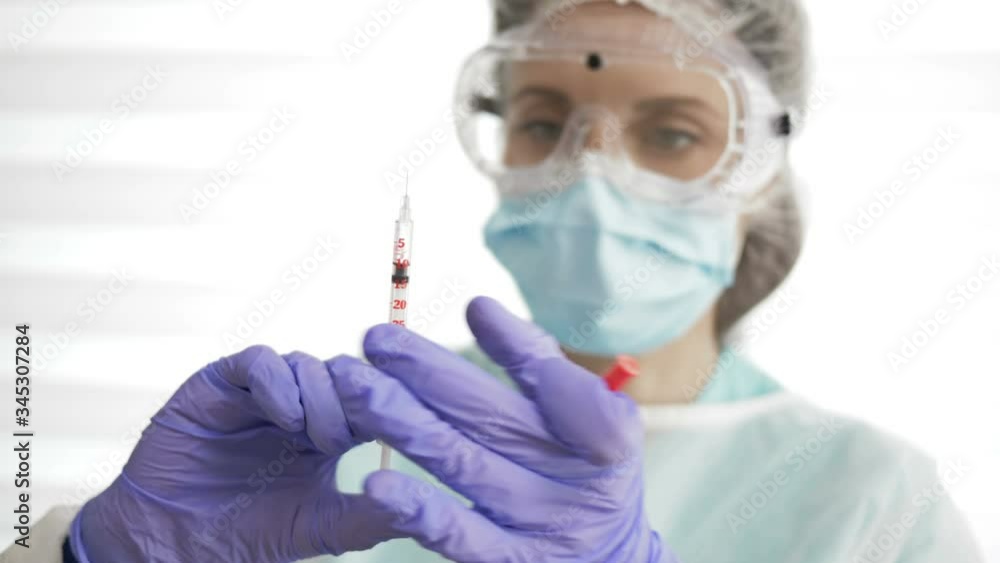 Portrait of a beautiful nurse in a protective suit with a syringe in her hands. Portrait of a beautiful nurse in a protective suit with a syringe in her hands.
