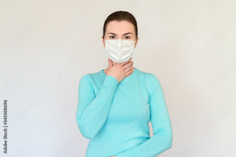 a woman in a blue sweater and medical mask clutched her throat. The concept of the fight against the virus, infection, fear a woman in a blue sweater and medical mask clutched her throat. The concept of the fight against the virus, infection, fear