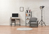 White brick wall concept, home interior decor, grey armchair, bookshelf and book with working table style.