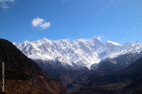 Nanga Bawa Peak  snowy mountains  blue sky  white clouds  folk houses and wild peach blossoms in the mountains 