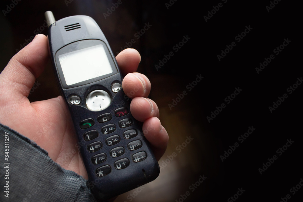 Old cell phone in hand on black background Old cell phone in hand on black background