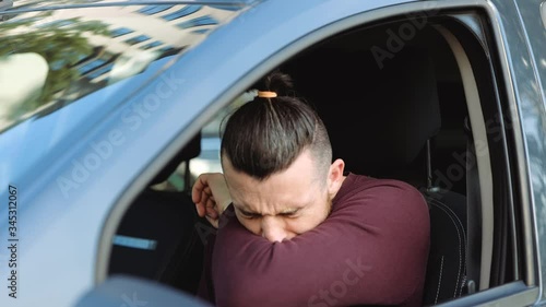 Young man inside car. Guy sit in front and caughing into hand. Suffer from strong pain in sore throat. Sick ill person in car. Caughing in slow motion. photo