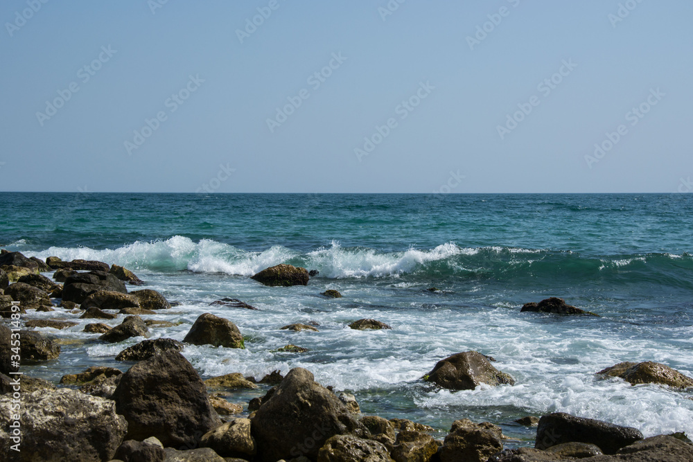 Beautiful wild beach landscape, sunny day, water waves hitting the cliffs, nature summertime scene Beautiful wild beach landscape, sunny day, water waves hitting the cliffs, nature summertime scene