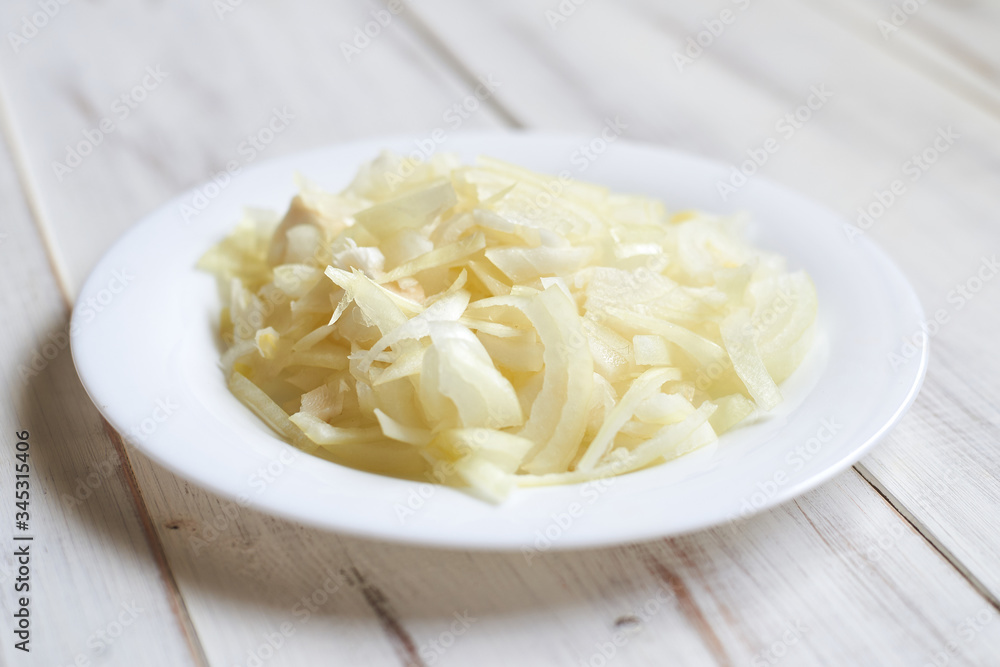 Sliced onions on a plate on a wooden background. Preparing for the recipe. Sliced onions on a plate on a wooden background. Preparing for the recipe.