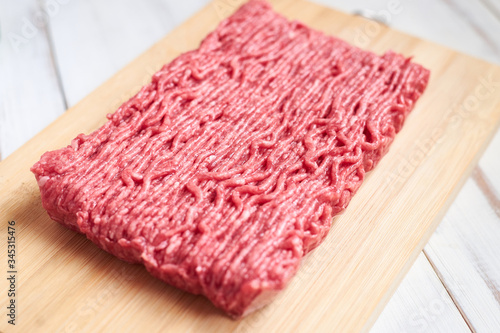 Raw minced meat on a wooden background.