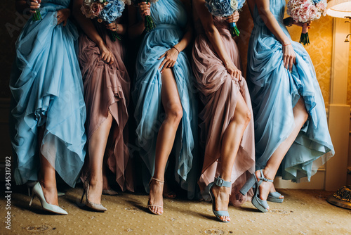 Girl in colored dresses with bouquets in hands. Bridesmaids in blue and brown dresses.