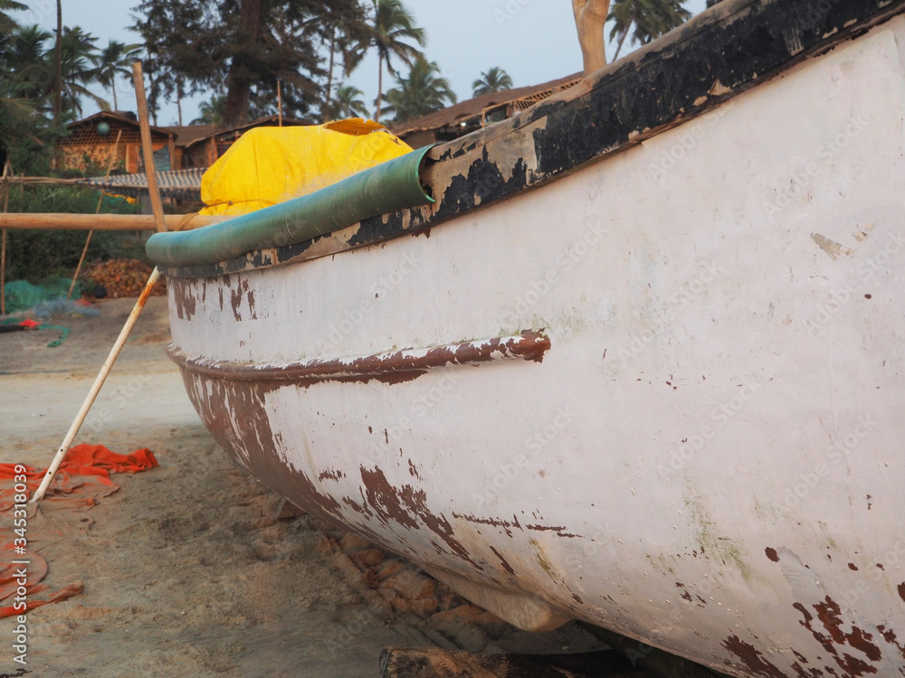 Bottom view of an old battered fishing wooden boat standing on a sandy beach. Bottom view of an old battered fishing wooden boat standing on a sandy beach.