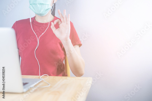 Asian woman wear hygiene protective mask to protect COVID 19, making facetime video call with smartphone at home, social distancing, working from home, work remotely concept.
