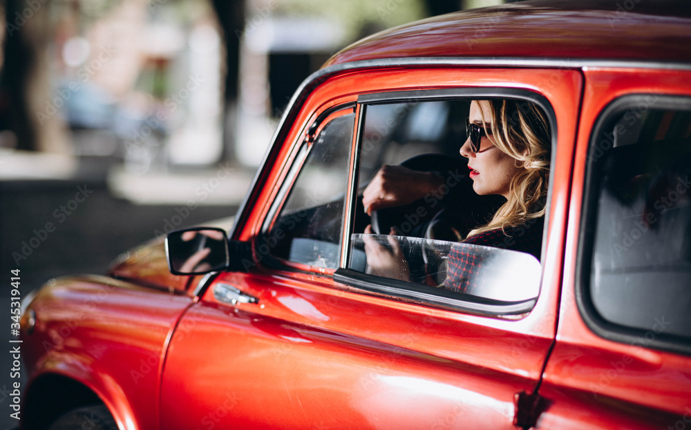 Caucasian blonde woman in red retro car driving at night in james bond style Caucasian blonde woman in red retro car driving at night in james bond style