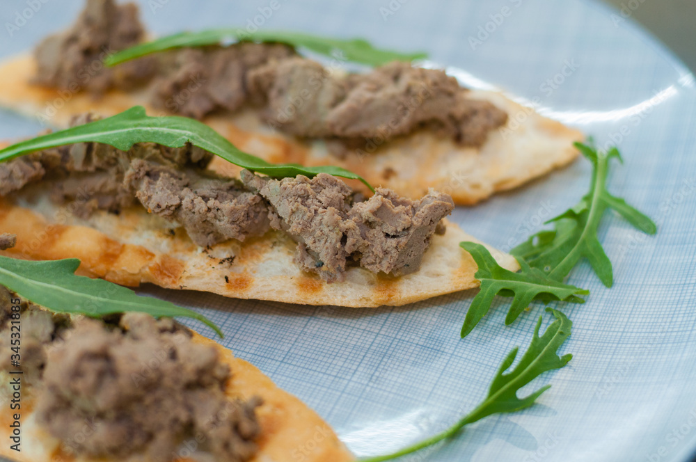 Croutons with paste and arugula. Festive appetizer, New Year's Italian dish. Side and top view, close-up Croutons with paste and arugula. Festive appetizer, New Year's Italian dish. Side and top view, close-up