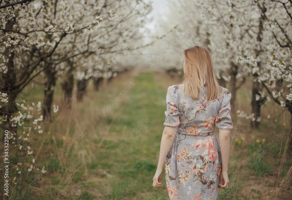 Beautiful girl in a flowering garden. Cherry garden. Summertime Concepts. Closeup Portrait of Positive. happy young woman enjoying smell in a flowering spring garden Beautiful girl in a flowering garden. Cherry garden. Summertime Concepts. Closeup Portrait of Positive. happy young woman enjoying smell in a flowering spring garden