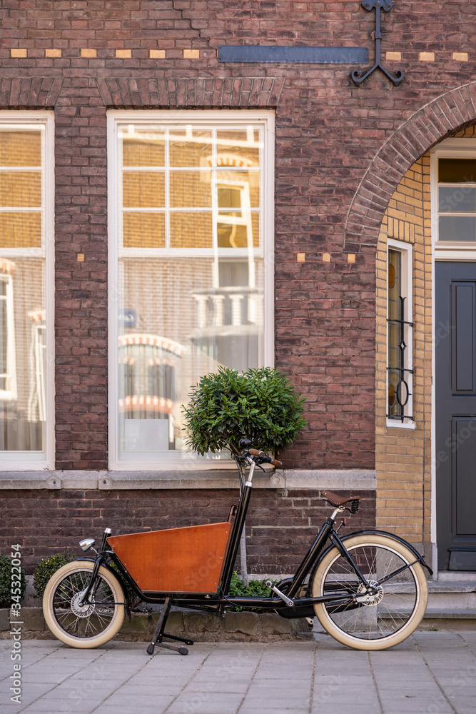 Typical Dutch carrier bicycle parked in front of a house. Modern urban parents use these carrier bikes to transport their groceries or children