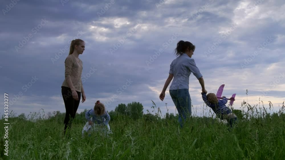 Family Playing with Toy Airplanes in Grass Field. Happy Mother and Children. Spring Evening Rural Nature Family Playing with Toy Airplanes in Grass Field. Happy Mother and Children. Spring Evening Rural Nature
