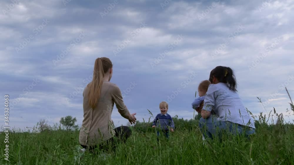 Happy Children Running in the Field Towards Mothers Embraces Hugging in Arms. Rural Sunset Evening Scenery Landscape Happy Children Running in the Field Towards Mothers Embraces Hugging in Arms. Rural Sunset Evening Scenery Landscape