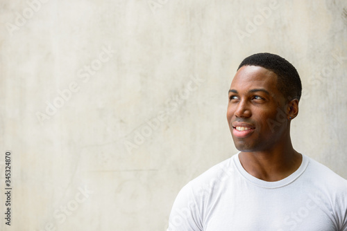 Face of happy young handsome African man thinking