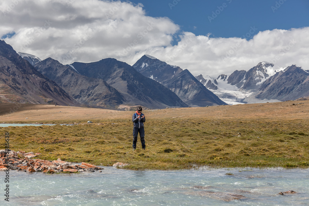 A tourist looks at a photograph of the mountains of the Mongolian Altai on its mobile phone.