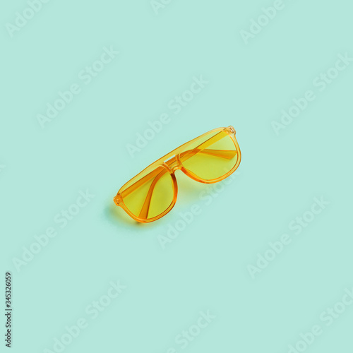 Yellow transparent frame trendy sunglasses on abstract mint background isolated. Copy space. Summer concept.