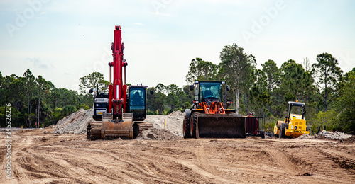 Heavy equipment - an excavator and bulldozer - sit idle at a construction site for a new road