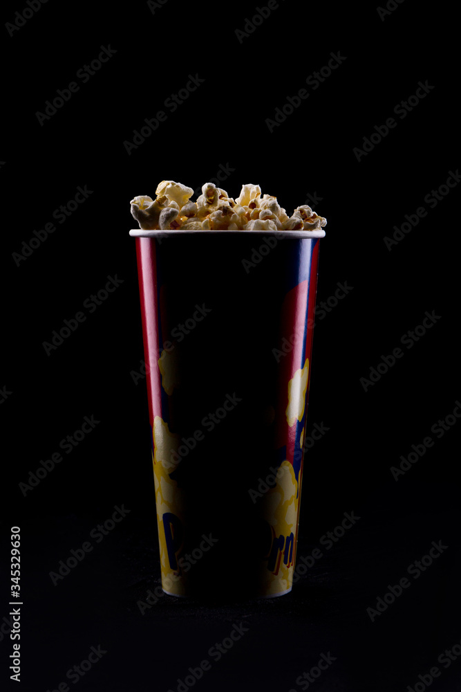 Paper cup with tasty popcorn on black background. Close-up salty popcorn. Paper cup with tasty popcorn on black background. Close-up salty popcorn.