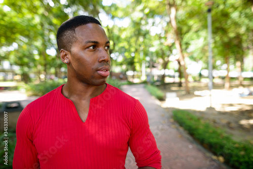 Face of young handsome African man thinking at the park