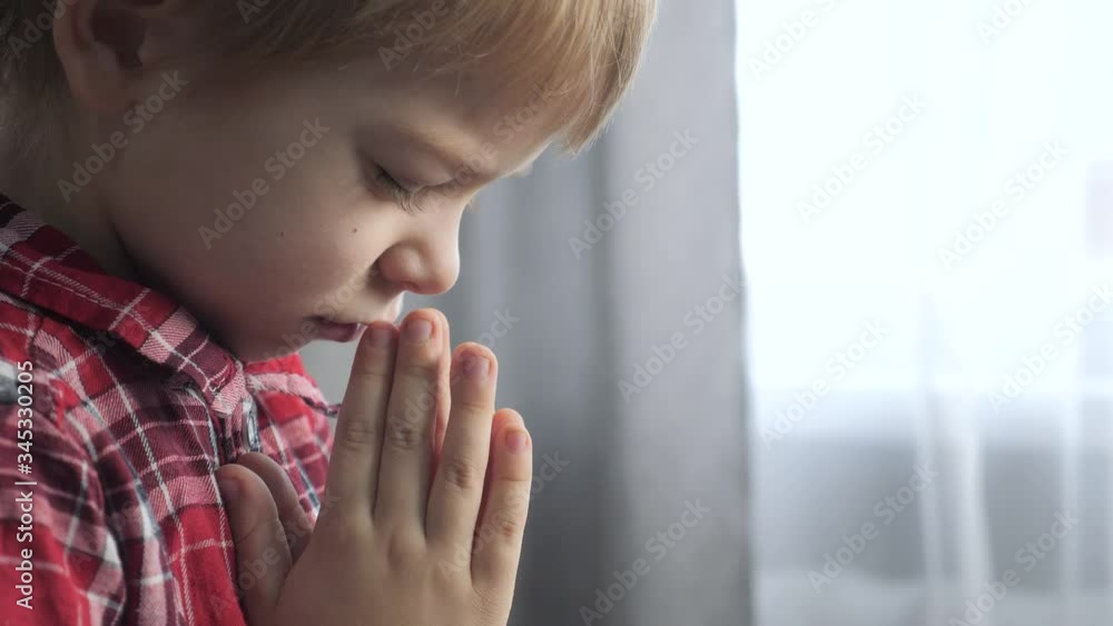 little son boy makes a wish prays bedtime religion concept. prayer child indoors praying by bed in lifestyle front of window little son boy makes a wish prays bedtime religion concept. prayer child indoors praying by bed in lifestyle front of window