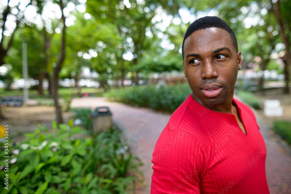 Face of young handsome African man looking back at the park Face of young handsome African man looking back at the park