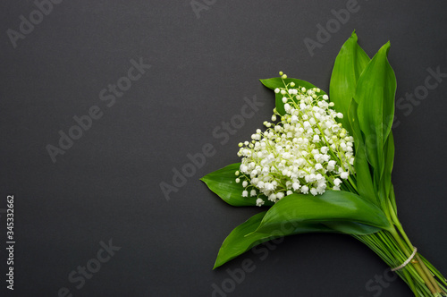 Beautiful bouquet of lilies of the valley on a dark background, top view