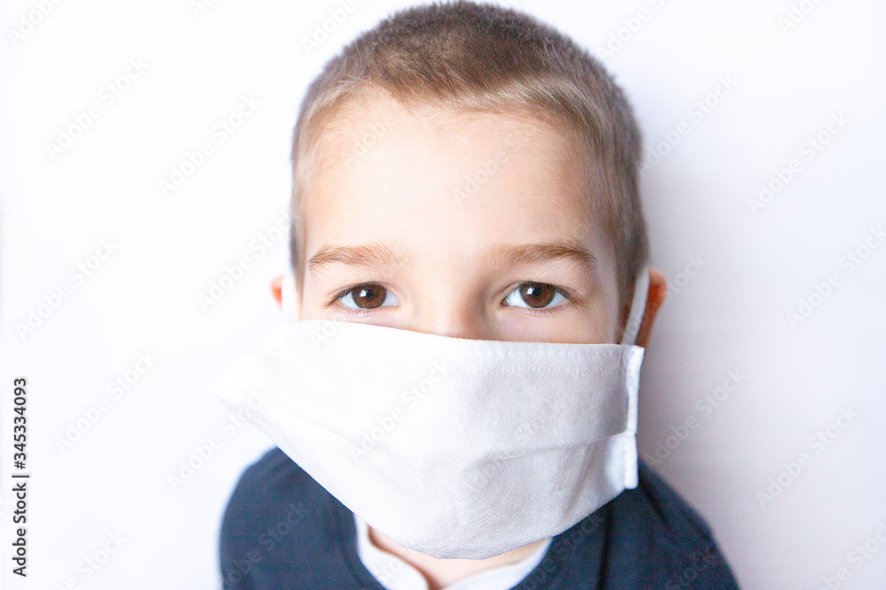 Boy child with big brown eyes wearing medicine disposable mask, white background Boy child with big brown eyes wearing medicine disposable mask, white background