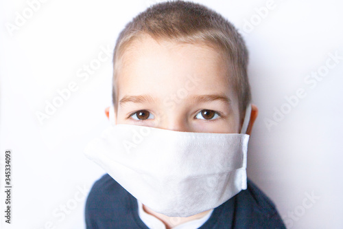 Boy child with big brown eyes wearing medicine disposable mask  white background