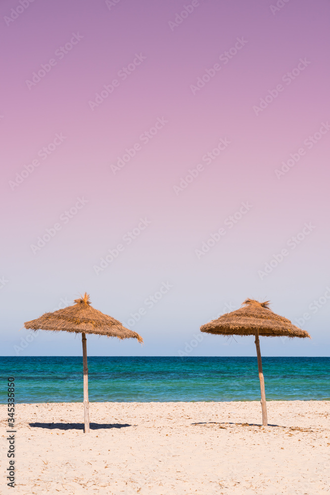 two beach umbrellas on the sandy beach at colorful sunset