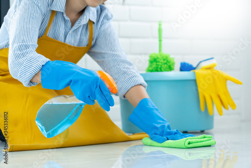 Photos Housekeeper maid wearing rubber gloves with cloth cleaning or applying floor care and cleaners at home, housework and housekeeping concept